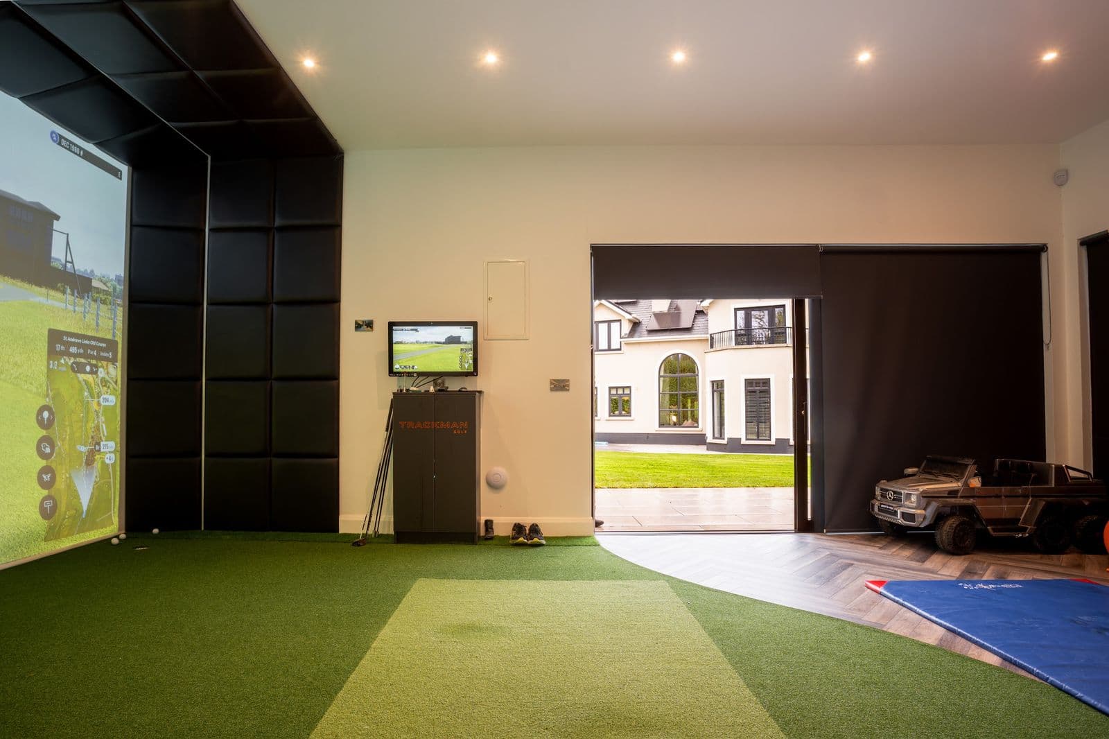 Interior of a home golf simulator room with impact screen and turf