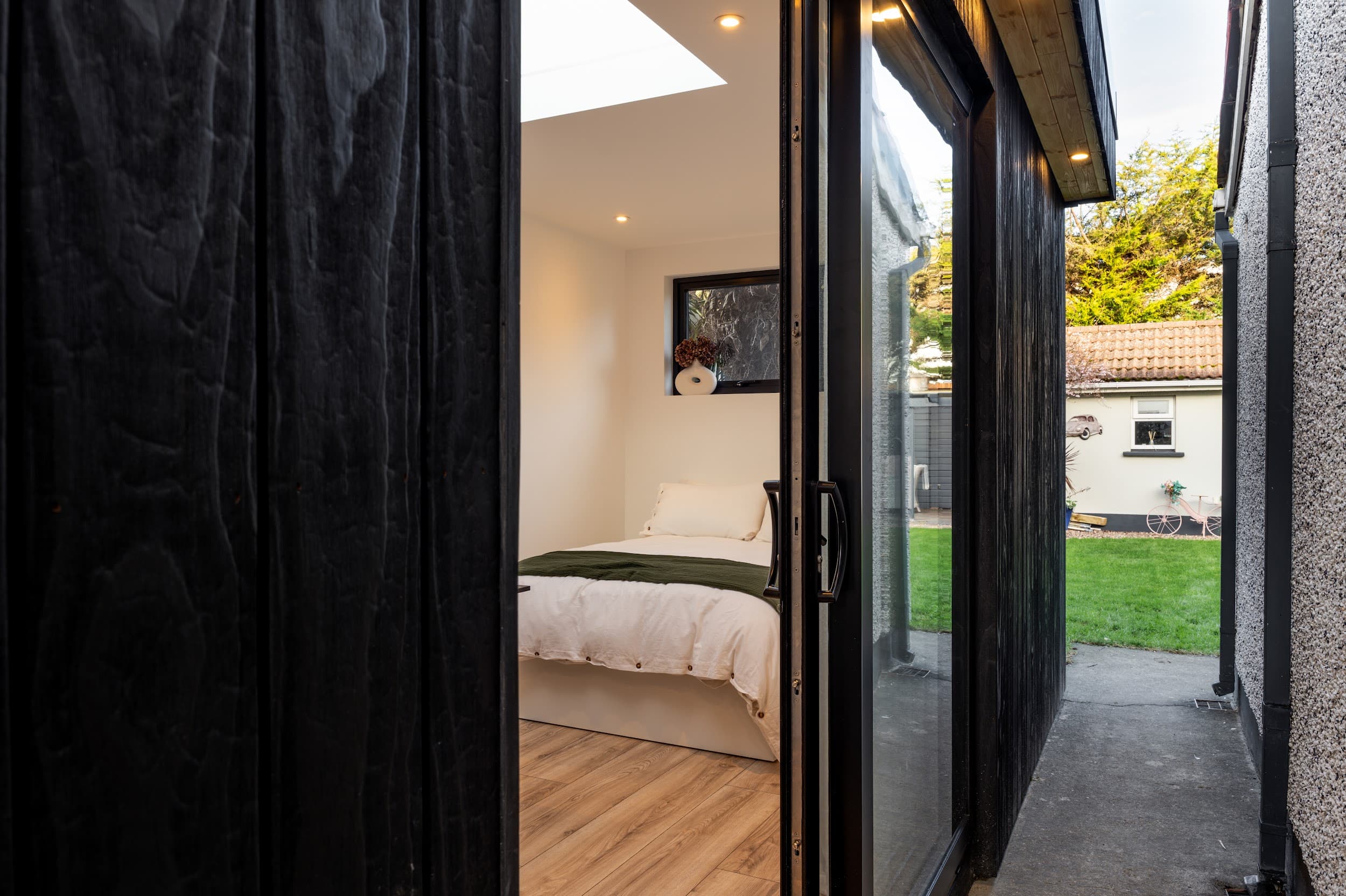 Elegant garden guest suite interior with bed, soft lighting and warm timber finish